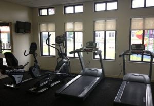 A gym with treadmills, elliptical machines, and a television.