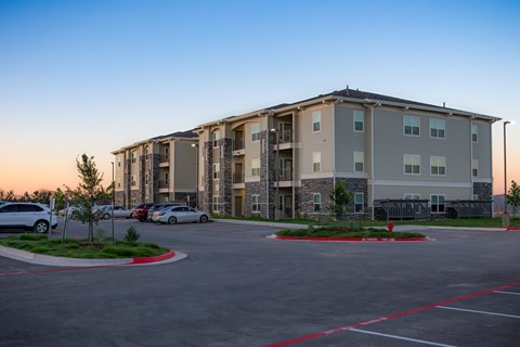 A parking lot in front of a large apartment building.