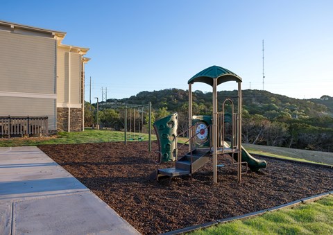 A playground with a green and white slide and a green canopy.