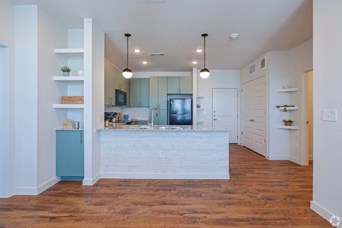 A kitchen with a white counter and wooden floors.