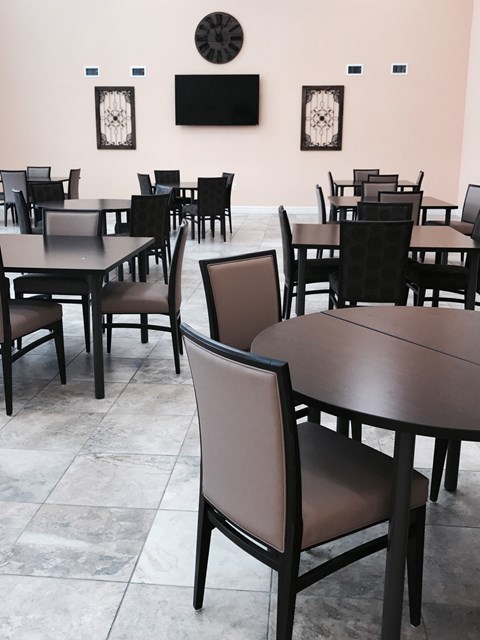 A room with tables and chairs and a clock on the wall.