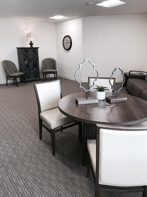 A conference room with a table, chairs, and a clock on the wall.