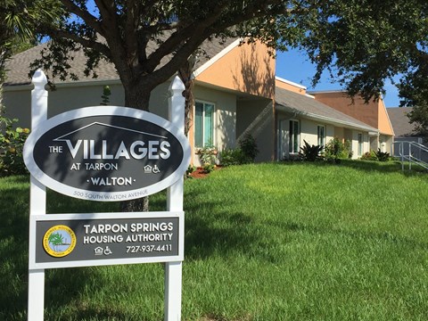 A sign for The Villages at Tarpon Walton in front of a house.