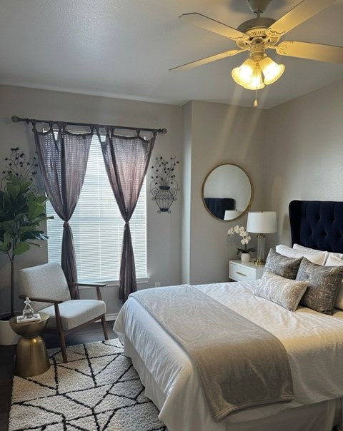 A bedroom with a large bed, a chair, and a ceiling fan.