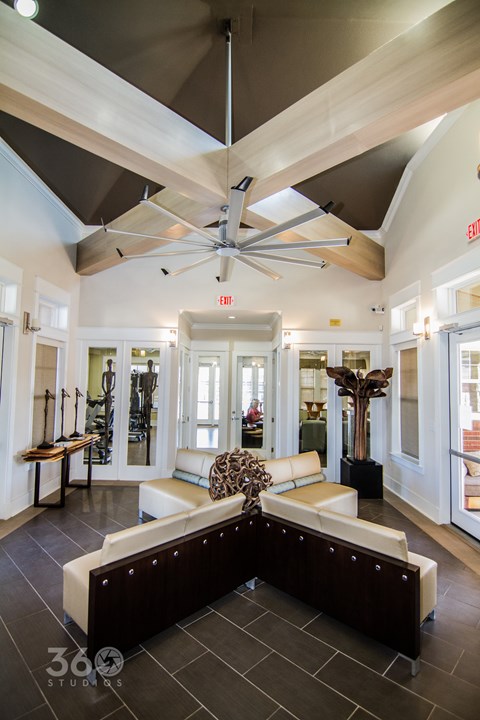 A spacious living room with a large sectional sofa and a ceiling fan.