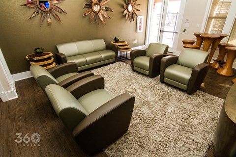 A living room with brown leather furniture and two sun-like wall decorations.