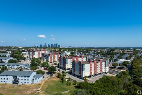 A view of a residential area with apartment buildings and a city skyline in the distance.