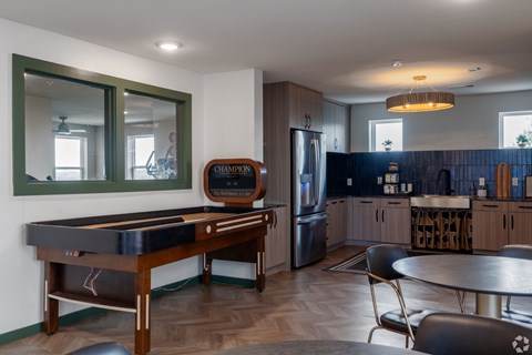 A pool table in a room with a fridge and a bar.