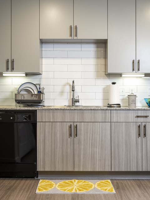 A black dishwasher is in a kitchen with a white tiled backsplash.