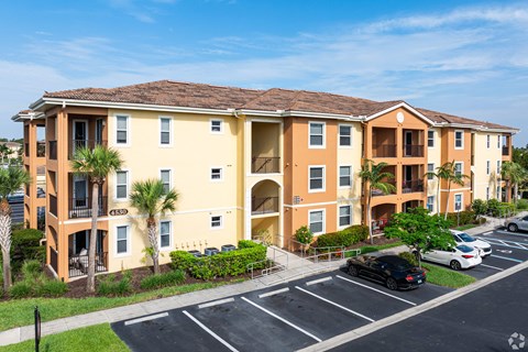 A large apartment complex with a parking lot in front.
