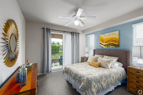 A bedroom with a bed, dresser, mirror, and a ceiling fan.