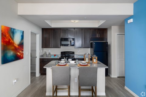A modern kitchen with a dining table set for two.