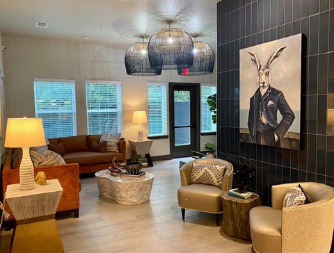 A living room with a brown couch, two chairs, a coffee table, and a painting of a rabbit on the wall.