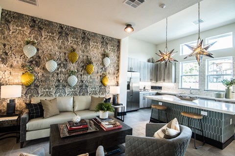 A modern living room with a grey sofa, a coffee table, and a kitchen in the background.