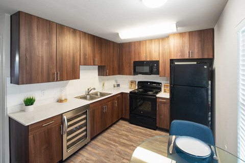 A kitchen with wooden cabinets and a black refrigerator.