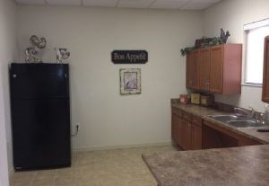 A kitchen with a black fridge and a sign that says Bon Appetit.