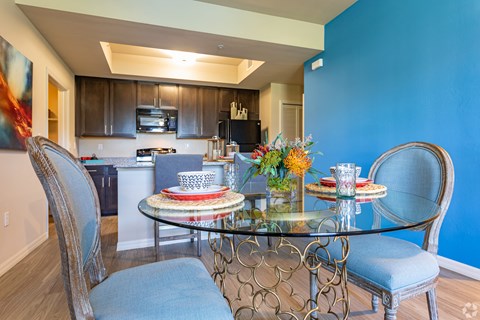 a dining room with a glass table and chairs and a kitchen