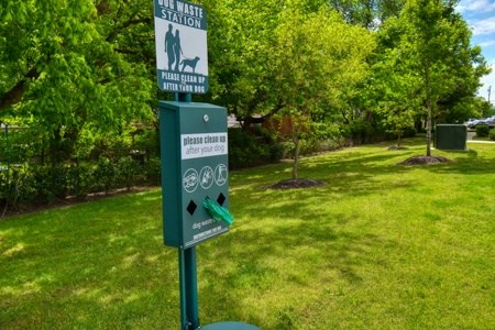 A sign in a park instructs people to clean up after their dogs.