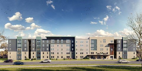 A large, modern apartment complex with a variety of buildings and a parking lot in front.