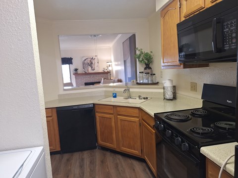 A kitchen with a black stove top oven and wooden cabinets.