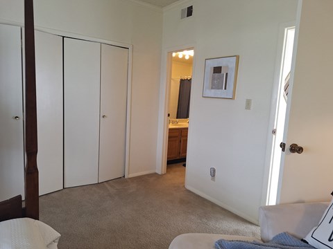 A bedroom with a white bed and a picture on the wall.