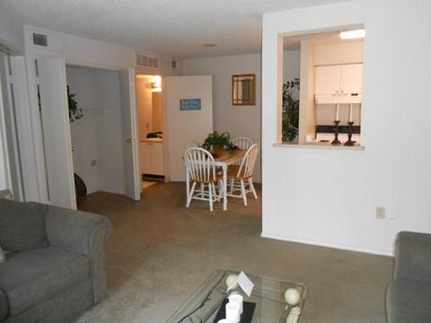 A living room with a grey couch and a glass table.