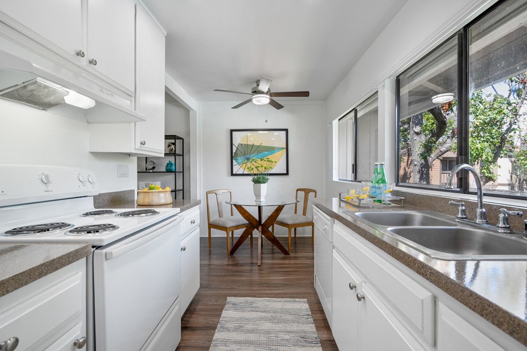 a kitchen with white cabinets and a sink and a window
