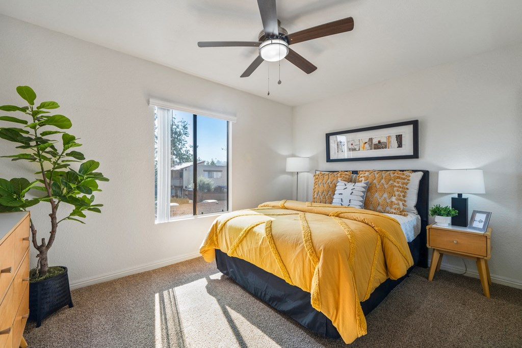 a bedroom with a yellow bed and a ceiling fan