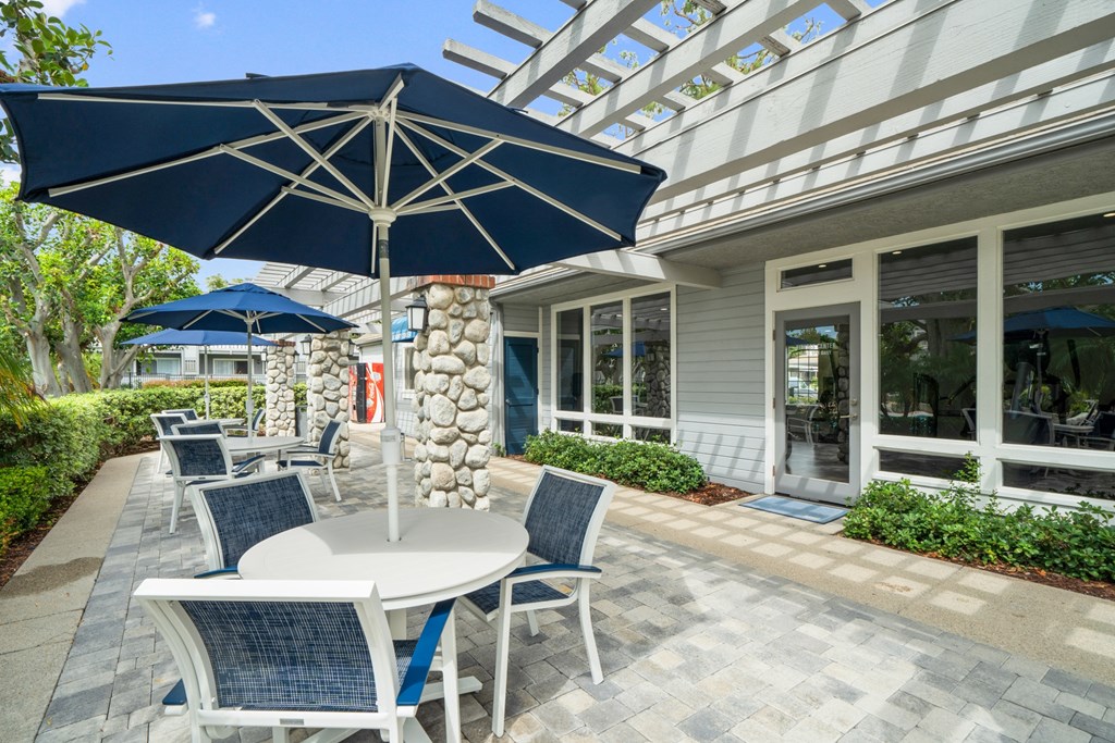 a patio with tables and umbrellas outside of a building