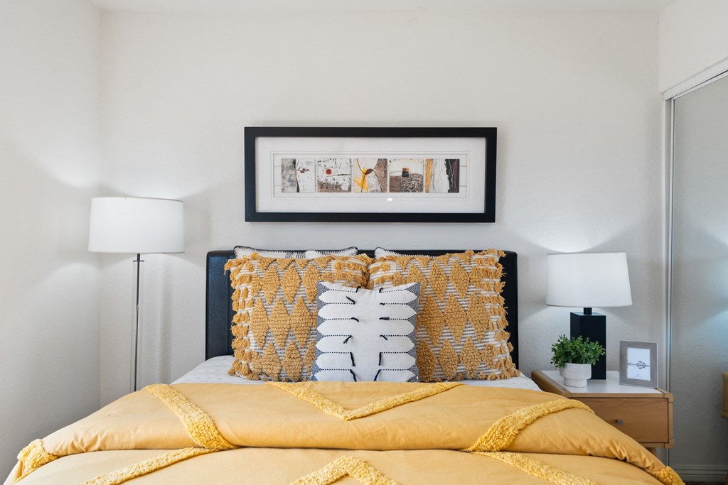 a bedroom with a yellow bed and yellow pillows and a picture on the wall