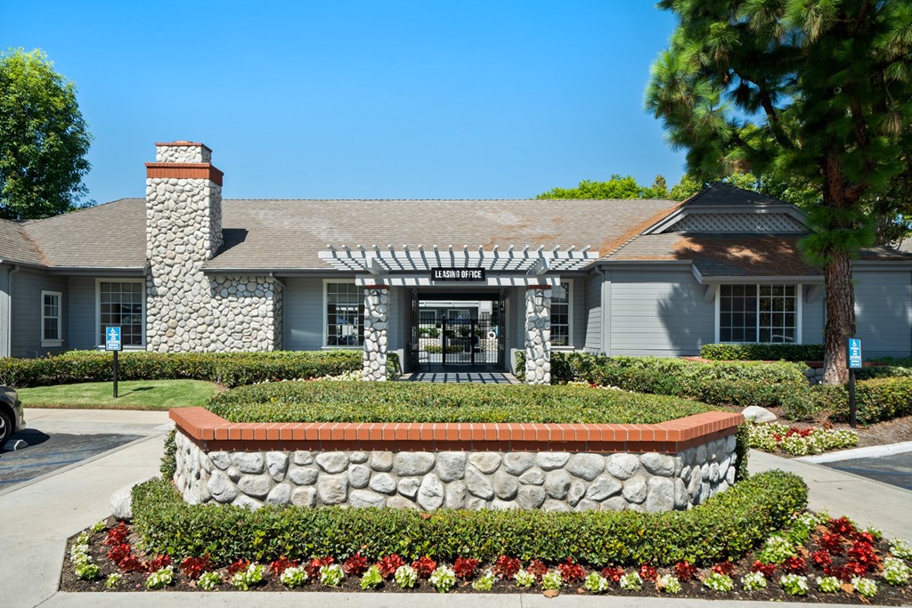 a house with a stone wall and a garden in front of it