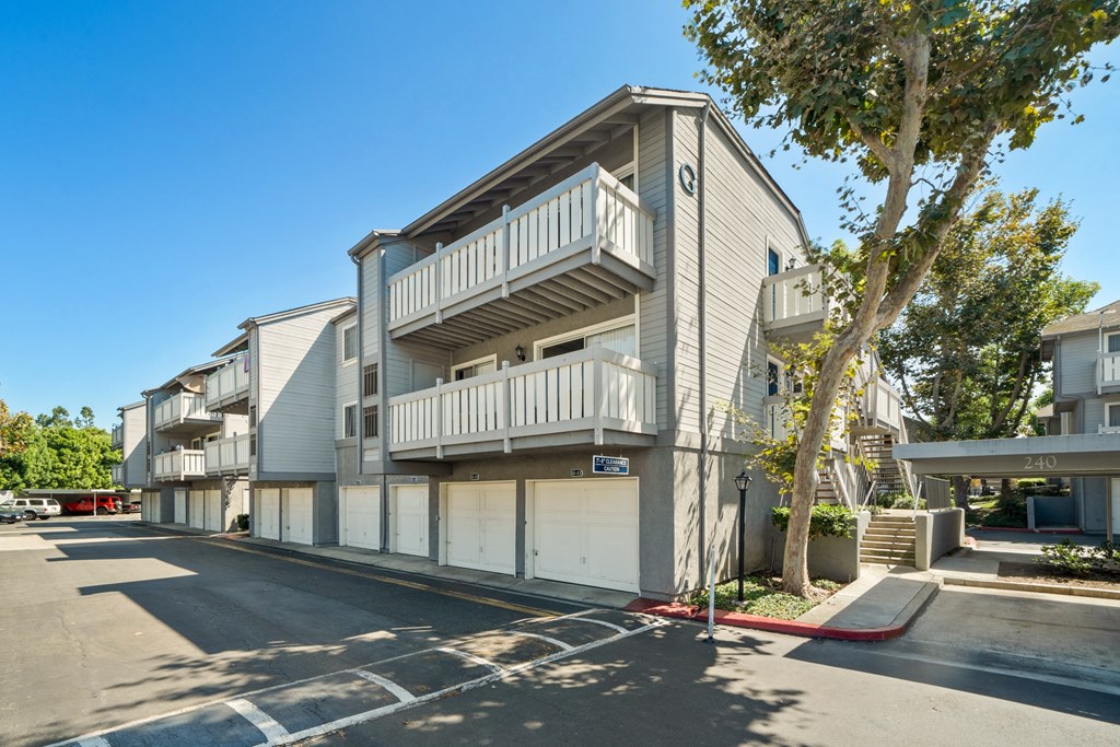 a street view of an apartment building with white balconies and garages