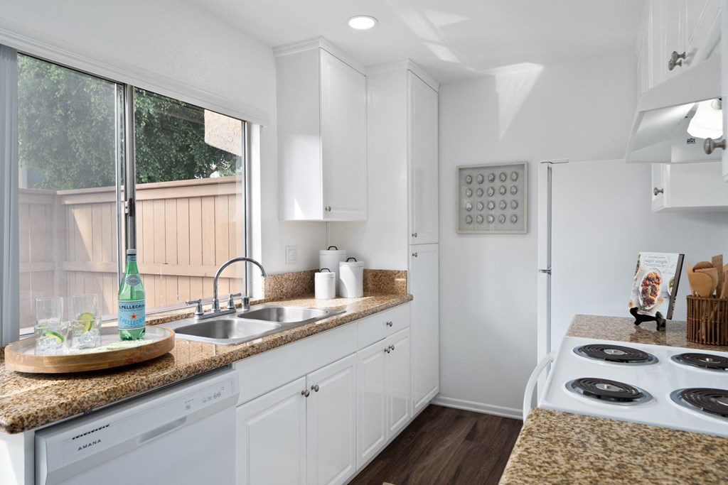 a kitchen with white cabinets and a counter top and a sink