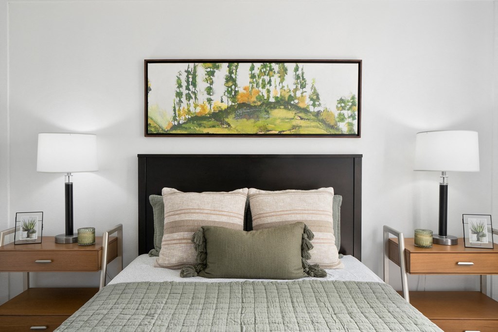 a bedroom with a bed and a painting on the wall