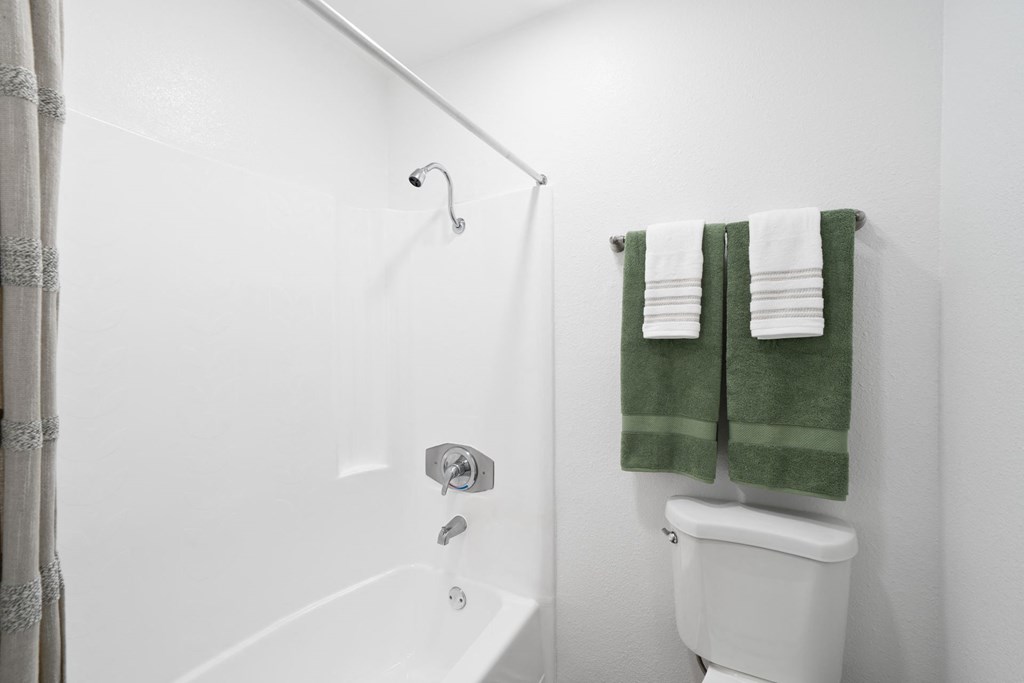 a bathroom with a toilet and a shower and towels