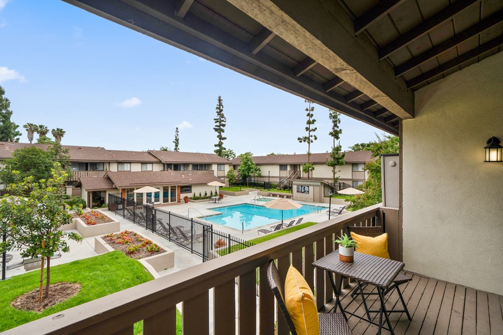 a balcony with a table and chairs and a swimming pool in the background
