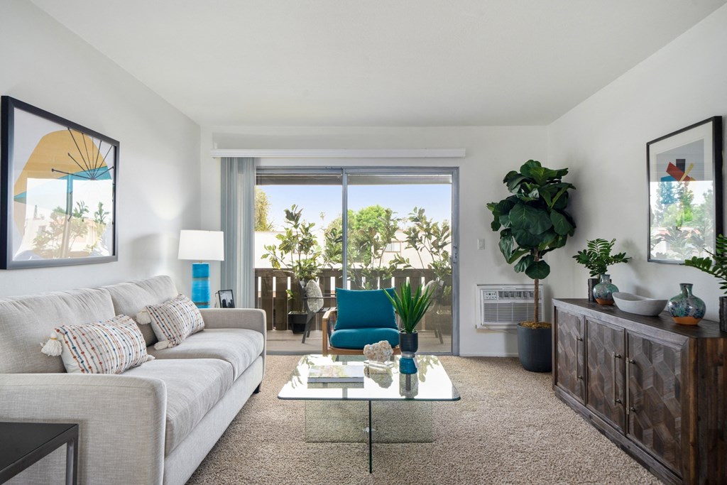 a living room with a white couch and coffee table and a sliding glass door leading to a