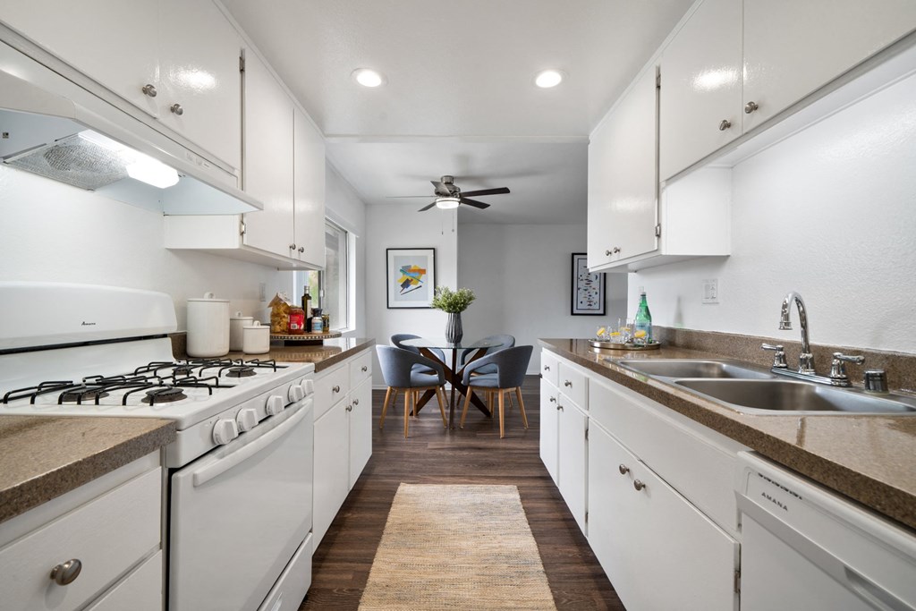 a kitchen with white cabinetry and a white stove top oven