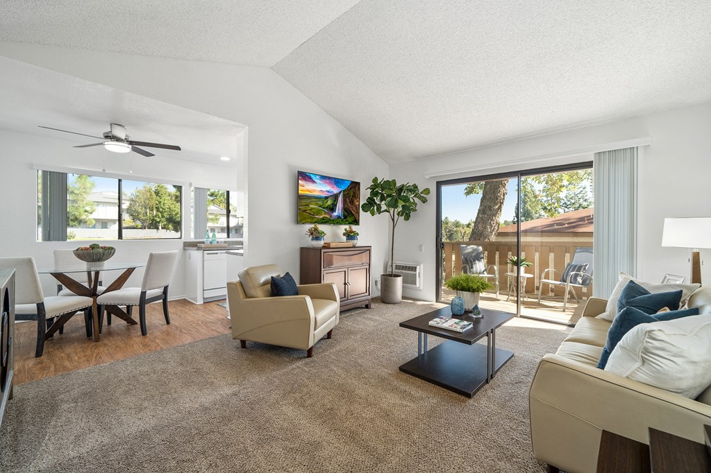 the living room and dining room of an apartment with couches and chairs