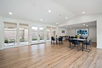 a living room with a dining room table and chairs and sliding glass doors
