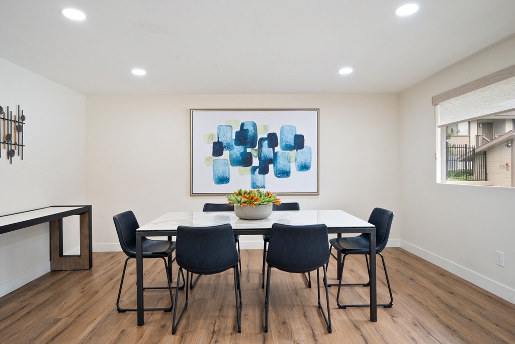 a dining room with a table and chairs and a painting on the wall