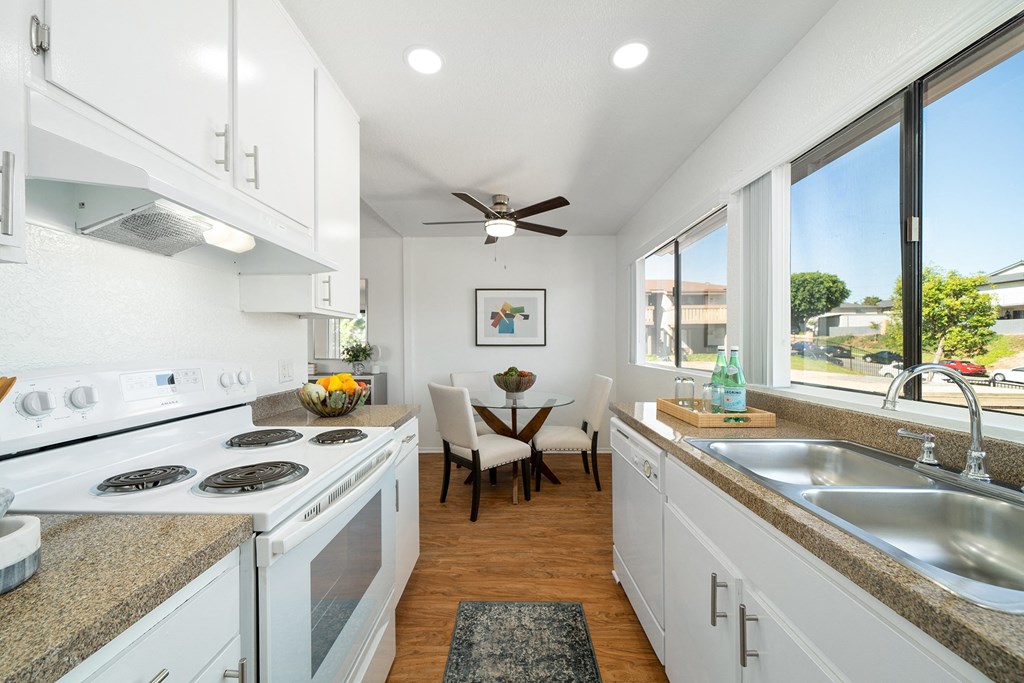 a kitchen with white cabinets and a sink and a window