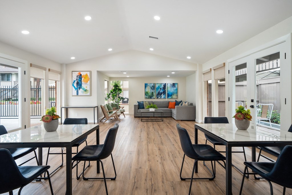 a dining area with tables and chairs and a living room in the background