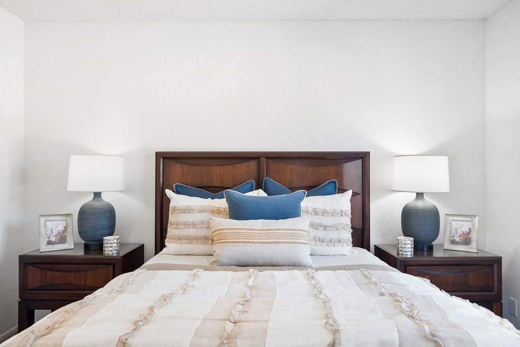 a bedroom with a bed with blue pillows and two lamps