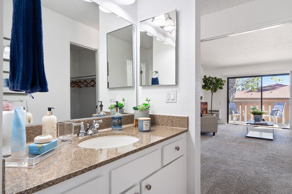 a bathroom with a sink and a mirror and a living room