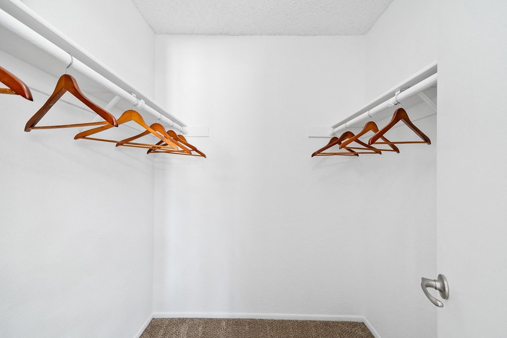 a closet with clothes hangers and a white wall