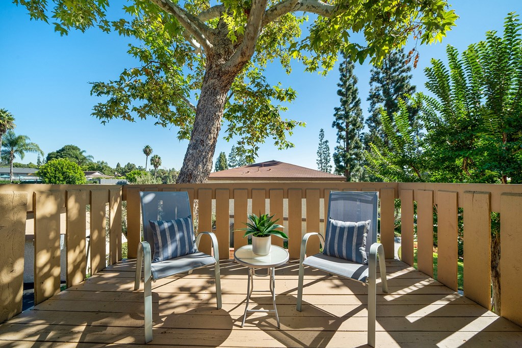 a deck with two chairs and a table and a tree