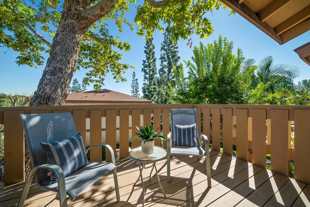 a patio with two chairs and a table on a deck