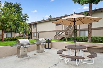 a patio with two barbecue pits and a table with an umbrella