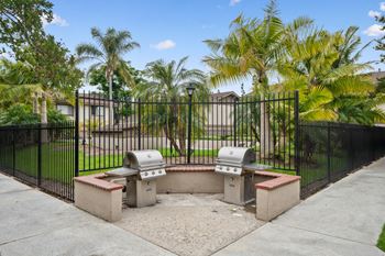 a park with two barbecue pits in front of a fence